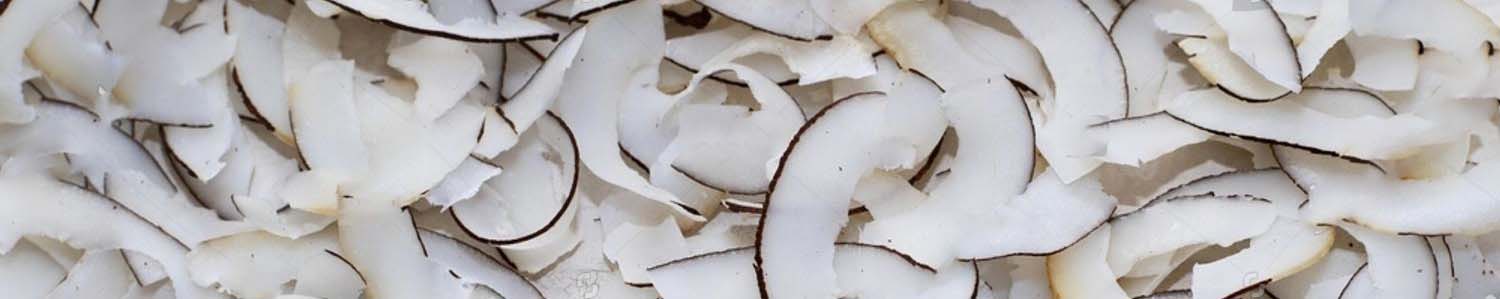 Primo piano a tutta immagine di numerose scaglie di cocco essiccato dalle numerose proprietà. Sottili e arricciate, con bordi scuri, che coprono l'intera superficie.