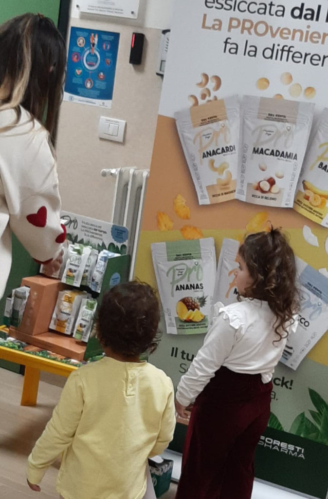 Due bambine di spalle osservano l'espositore di snack salutari Pro all'interno del reparto pediatrico dell'Ospedale Casa Sollievo della Sofferenza durante l'evento sulla prevenzione